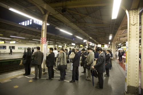 A line of Japanese business men waiting for (probably the last) train home